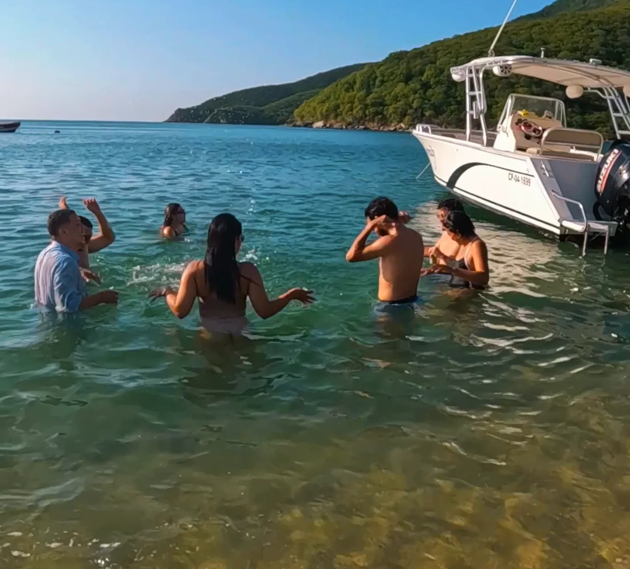 Personas disfrutando del agua junto a la embarcación.