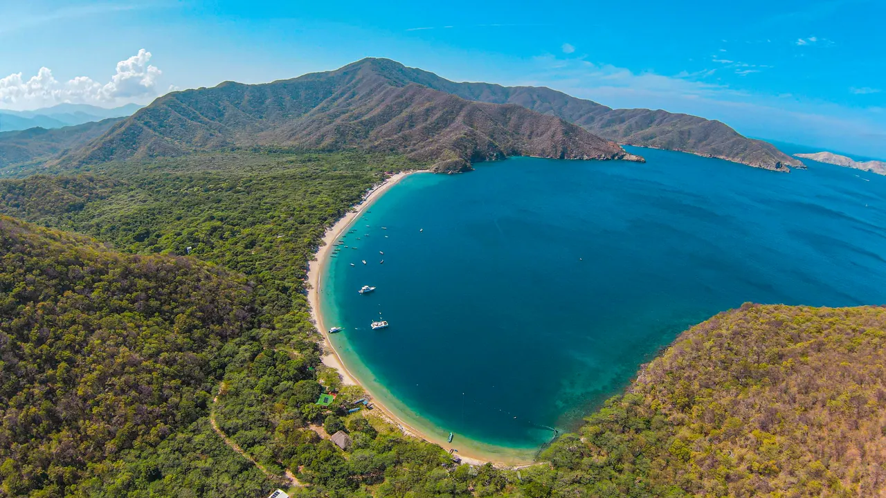 Vista aérea de Bahía Concha con su playa en media luna y las montañas del Parque Tayrona.