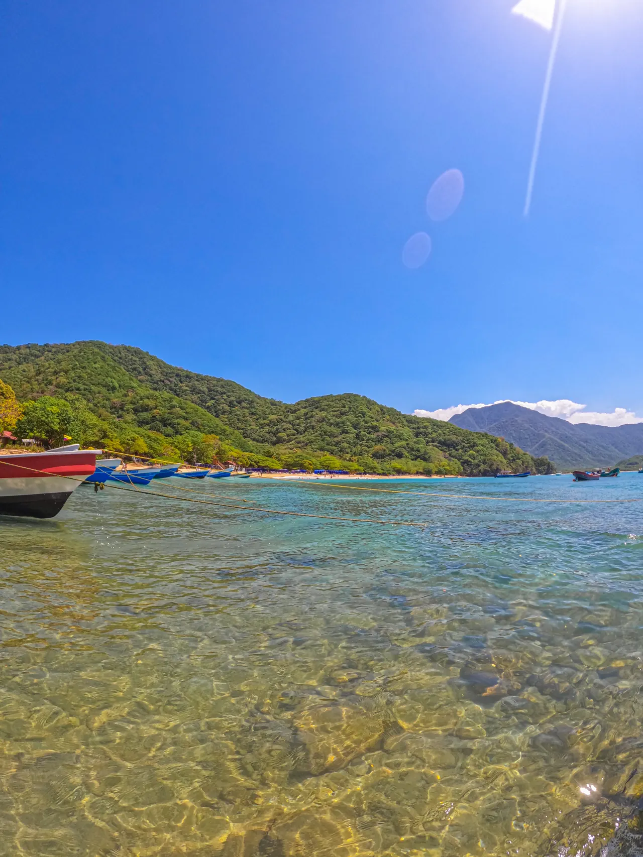 Crystal-clear water with boats in the background at Playa Cristal beach.