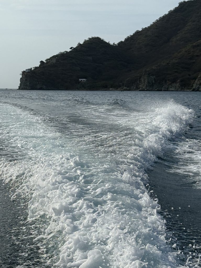The wake of the boat next to the cliffs.