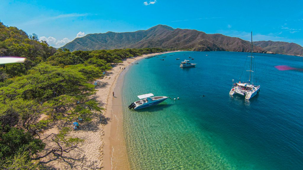 Bahía Concha Beach with small boats and a catamaran at anchor.